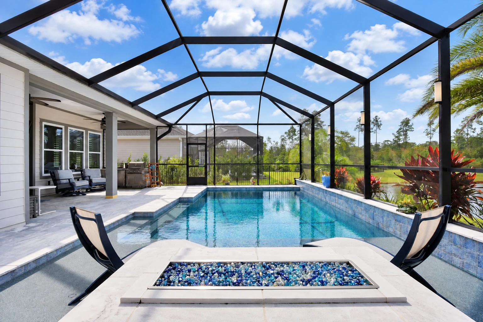 A screened patio enclosure surrounds a swimming pool, with a black-framed roof and a small fire feature in the foreground.